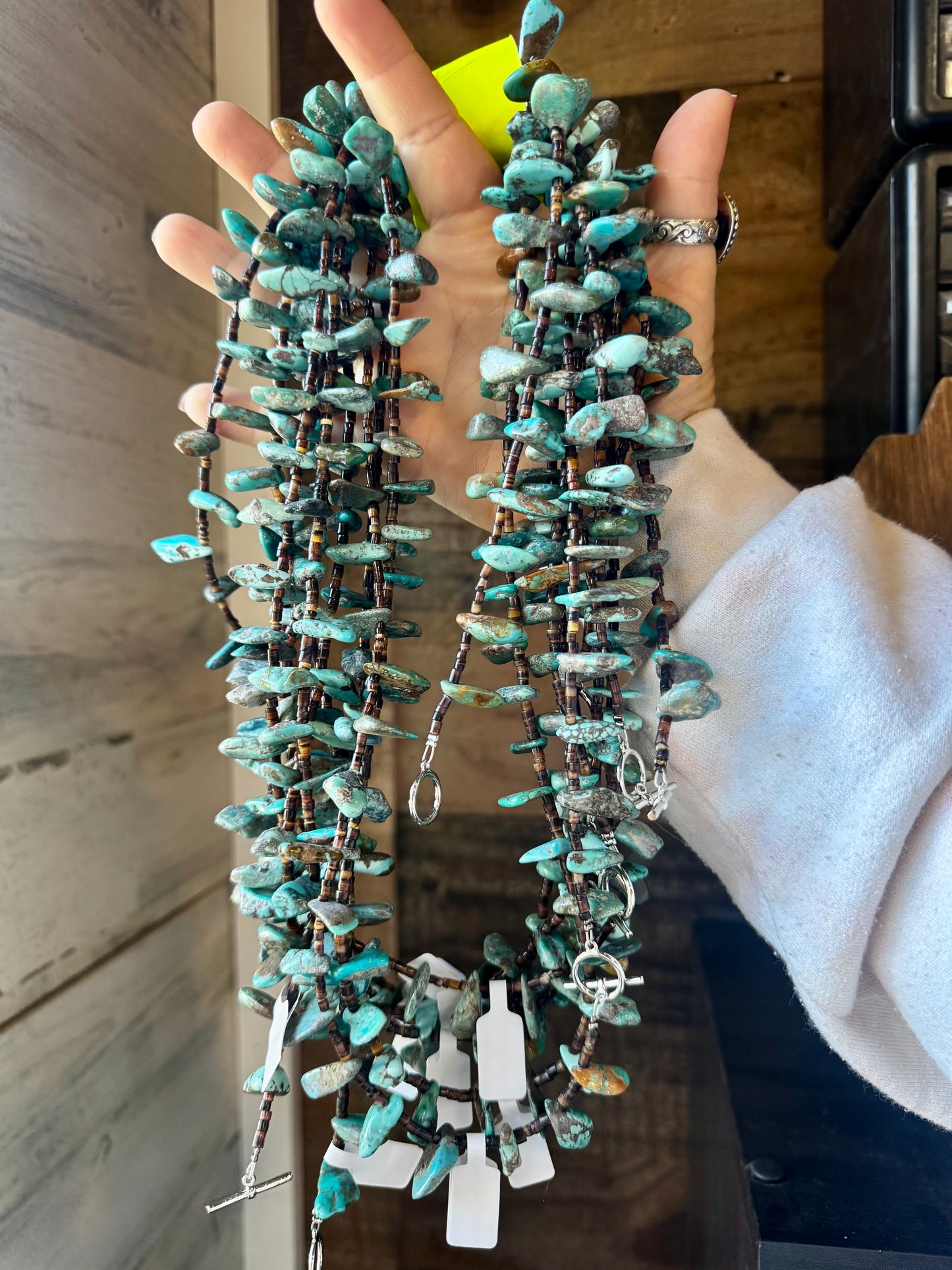 Handmade 30-inch necklace with 3mm dark shell beads and a real turquoise teardrop pendant. Silver-plated finish. Every turquoise stone is unique. Made in the USA by The Bijoux FAB. Limited quantity available.