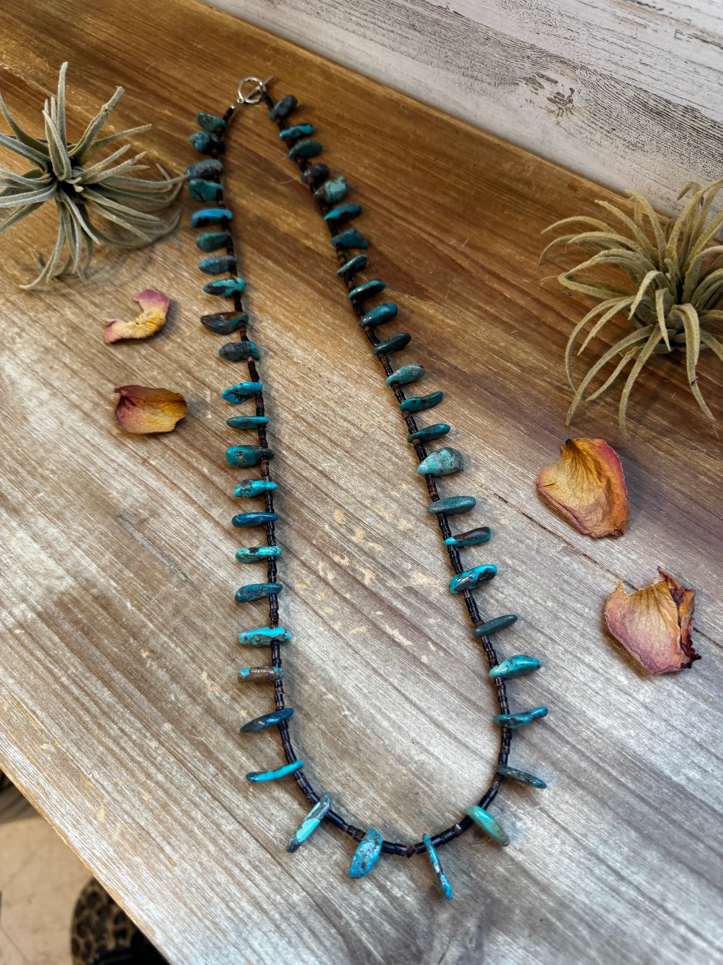 Handmade 30-inch necklace with 3mm dark shell beads and a real turquoise teardrop pendant. Silver-plated finish. Every turquoise stone is unique. Made in the USA by The Bijoux FAB. Limited quantity available.