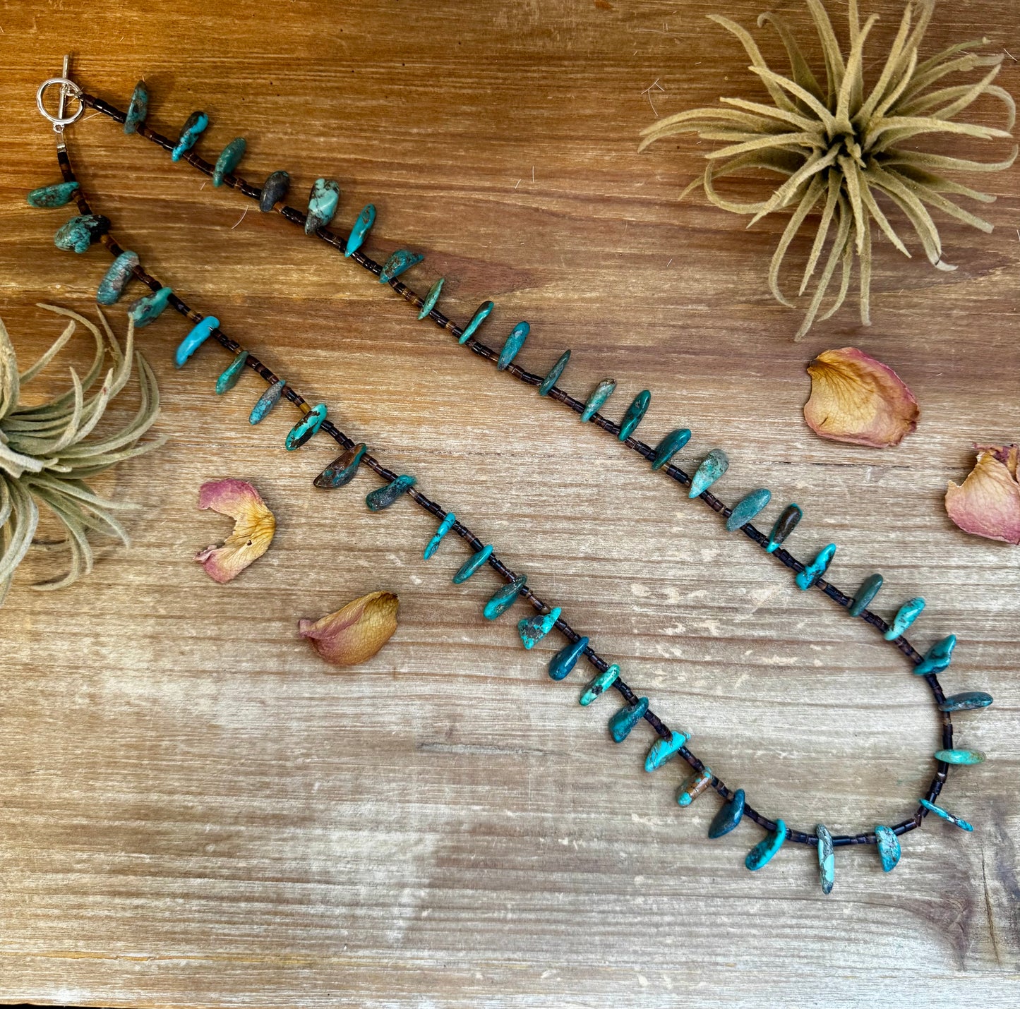Handmade 30-inch necklace with 3mm dark shell beads and a real turquoise teardrop pendant. Silver-plated finish. Every turquoise stone is unique. Made in the USA by The Bijoux FAB. Limited quantity available.